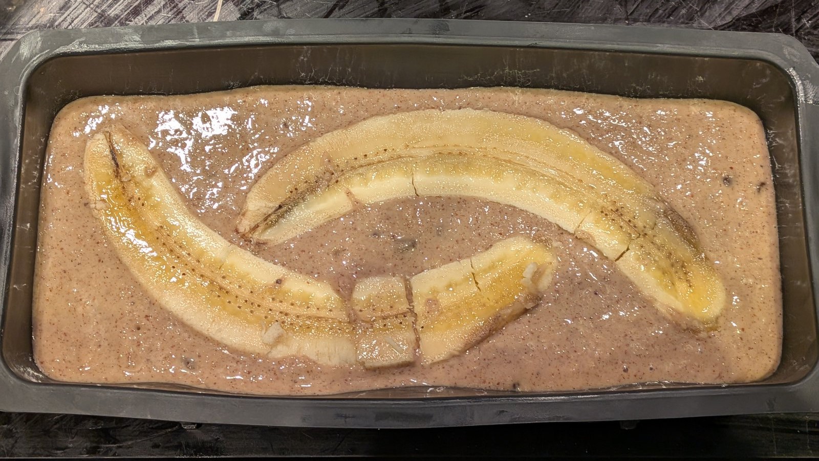 Gâteau à la banane sans gluten en moule à cake, banane fendue sur le dessus avant cuisson