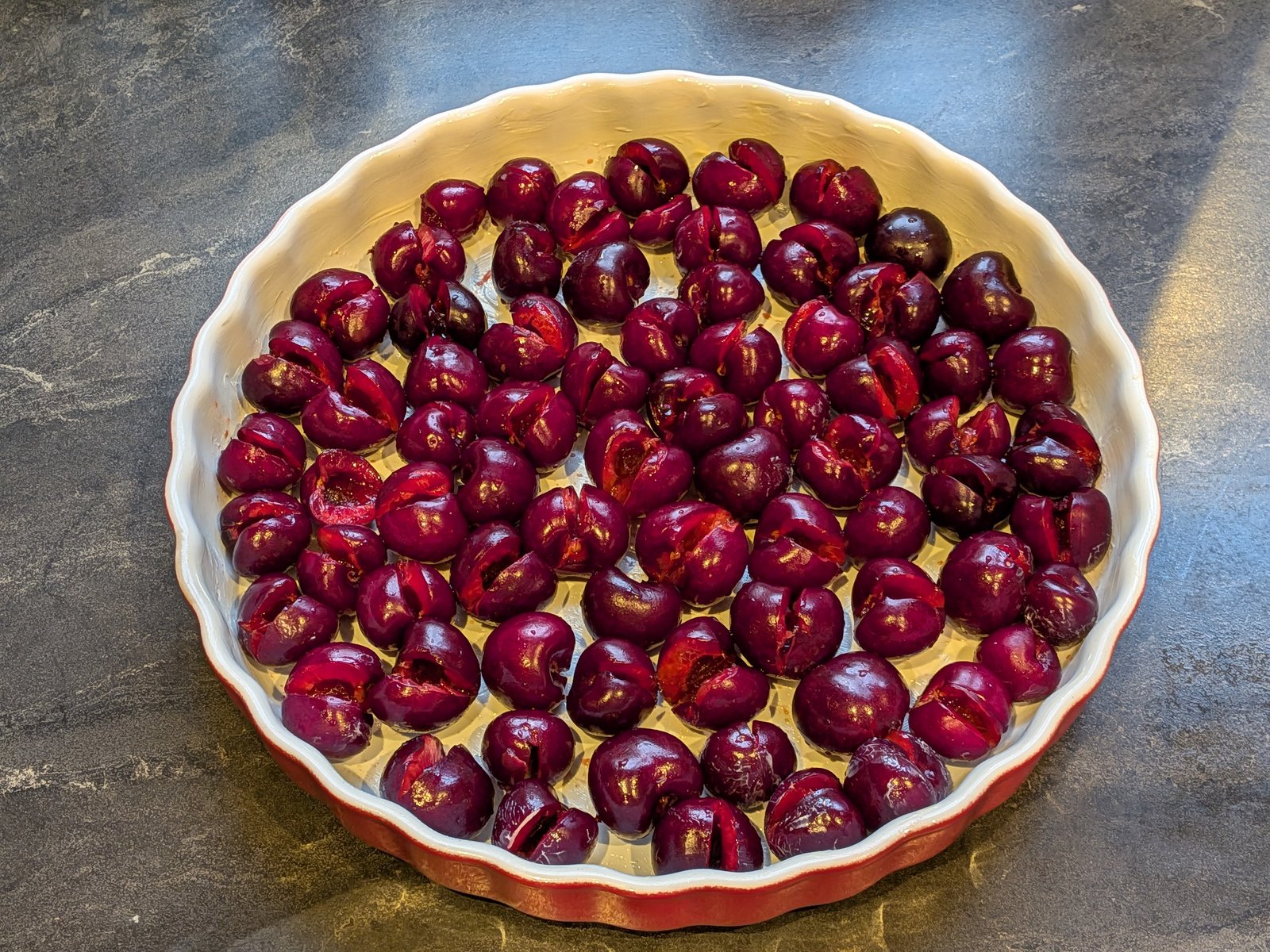 Cerises dénoyautées rangées dans le plat beurré, avant l'appareil